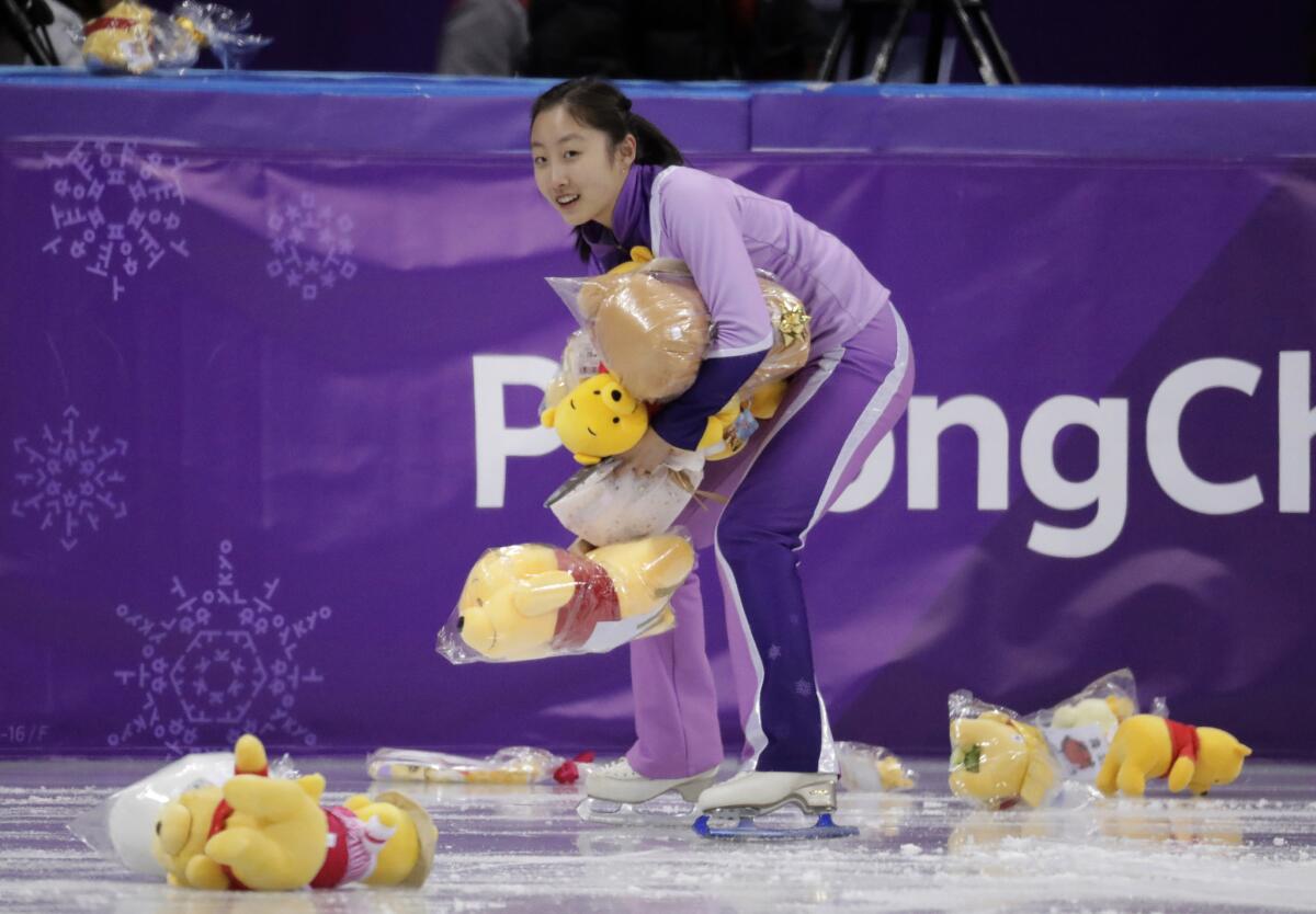 A skater collects Winnie The Pooh toys off the ice following Yuzuru Hanyu's performance.
