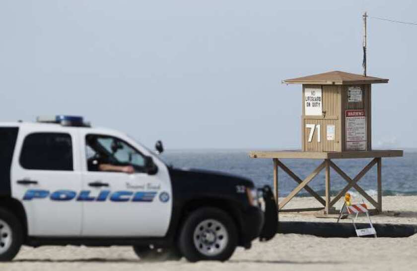 A Newport Beach police vehicle drives by a lifeguard tower.
