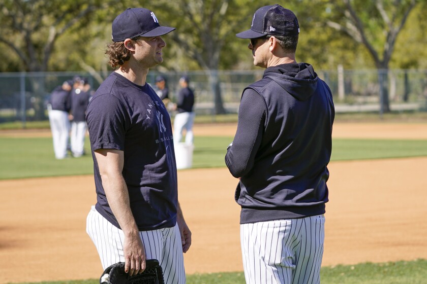 New York Yankees pitcher Gerrit Cole, left, talks with manager Aaron Boone during a spring training baseball workout, Monday, March 14, 2022, in Tampa, Fla. (AP Photo/John Raoux)