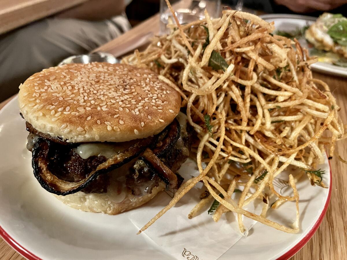 Lingua Franca burger on a sesame-seed bun with thin fries.