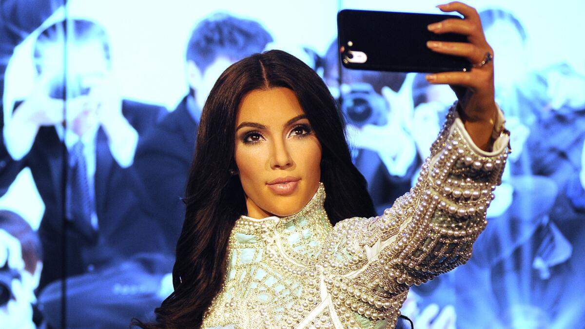 "Kim Kardashian" -- actually, a wax version of the reality star -- stands ready to snap a selfie at Madame Tussauds in London.