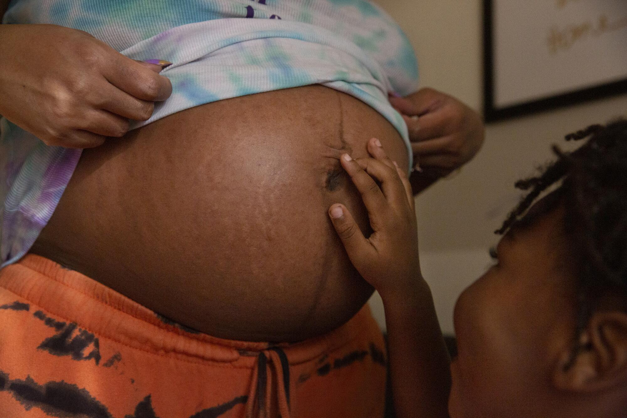 A boy touches his pregnant mother's belly