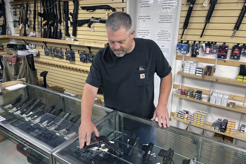 FILE — John Parkin, co-owner of Coyote Point Armory displays a handgun at his store in Burlingame, Calif., June 23, 2022. In response to the U.S. Supreme Court's ruling that allows more people to carry concealed weapons, California lawmakers, on Tuesday, June 28, 2022, moved to boost requirements and limit where firearms may be carried while staying within the high court's ruling. (AP Photo/Haven Daley, File)