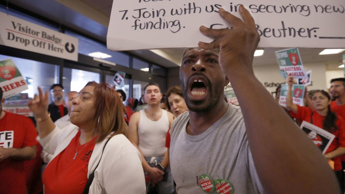 L.A. teachers union Vice President Cecily Myart-Cruz, left, and parent Todd Tyson lead chants during a recent rally in the lobby of L.A. Unified headquarters just west of downtown.