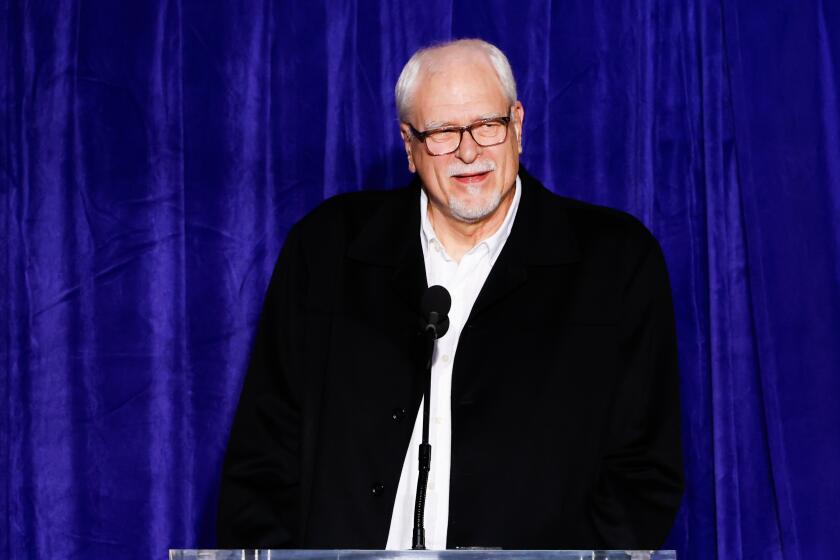 Phil Jackson stands at a podium and speaks as the Los Angeles Lakers unveil a statue honoring the late Kobe Bryant.
