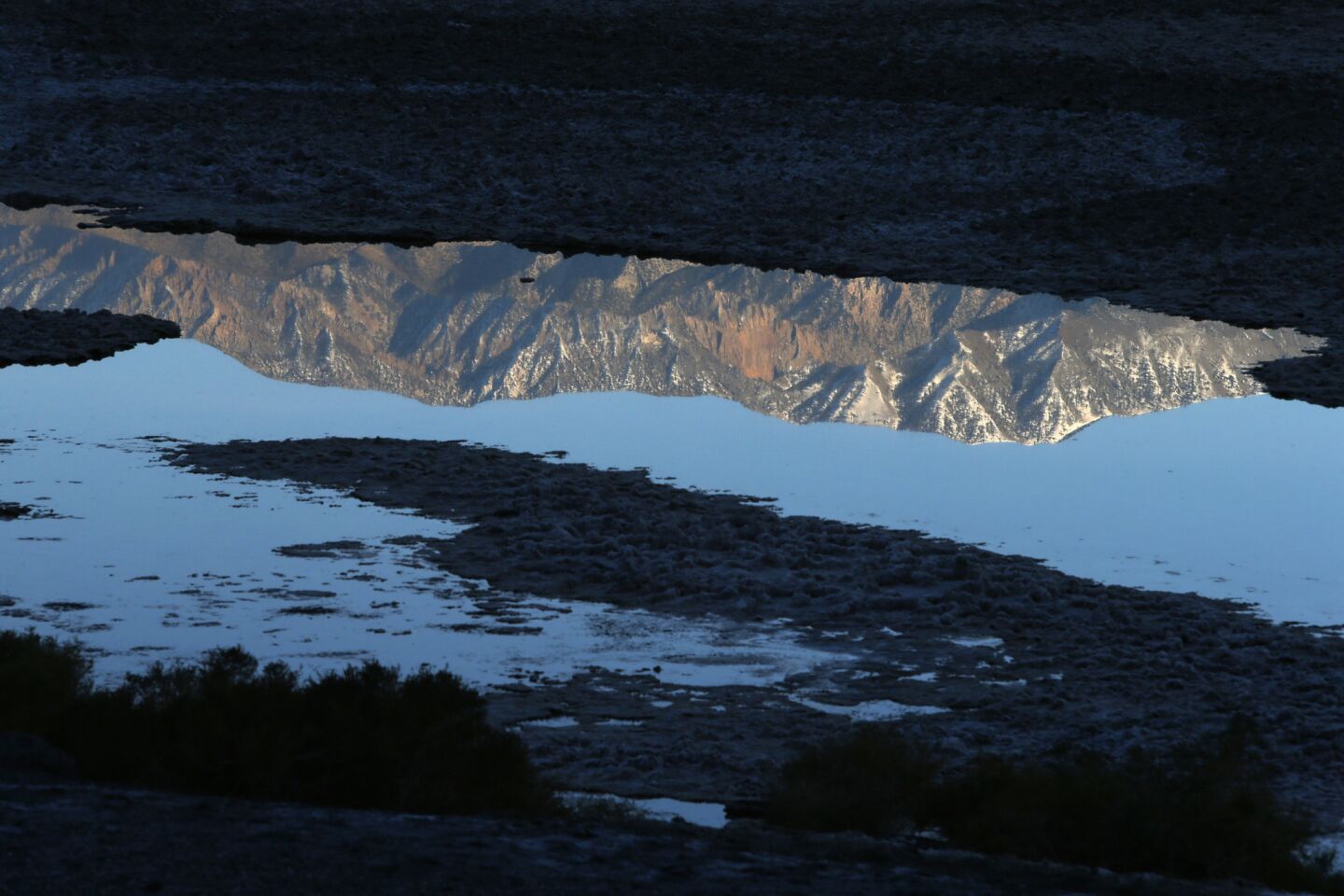 The highest spot in the park, Telescope Peak at 11,049 feet, is reflected in standing water in Death Valley's lowest place, Badwater Basin.