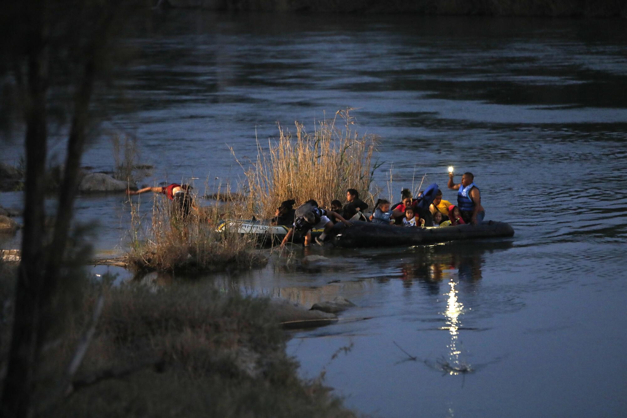 A group of people in inflatable rafts landing on a riverbank