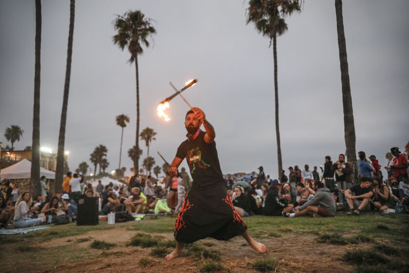 Nate Endless twirls a fire baton in Ocean Beach on Wednesday, July 29, 2020.(Photo by Sandy HUffaker for The San Diego Union-Tribune)