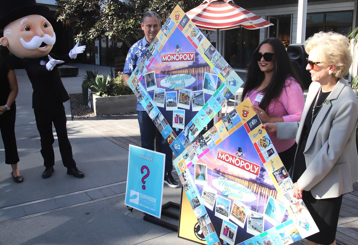 Officials take part in the official unveiling of "Monopoly: Huntington Beach edition" at Pacific City on Wednesday.