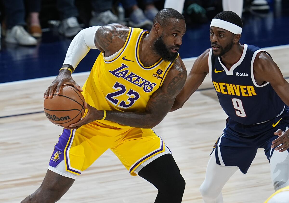 Lakers forward LeBron James, left, looks to pass the ball while defended by Nuggets forward Justin Holiday during Game 5.