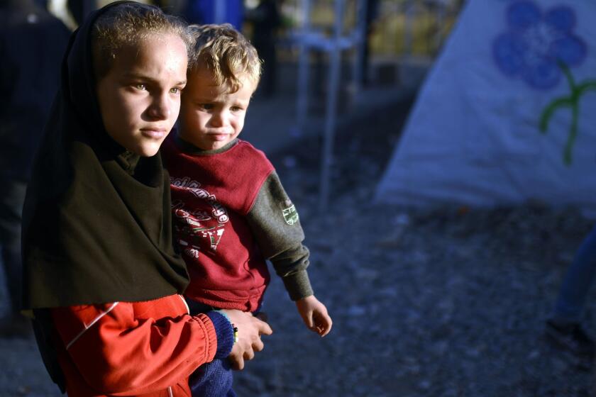 A girl carries a boy as migrants and refugees wait for a train heading to Serbia from the Greek-Macedonian border on November 5, 2015.