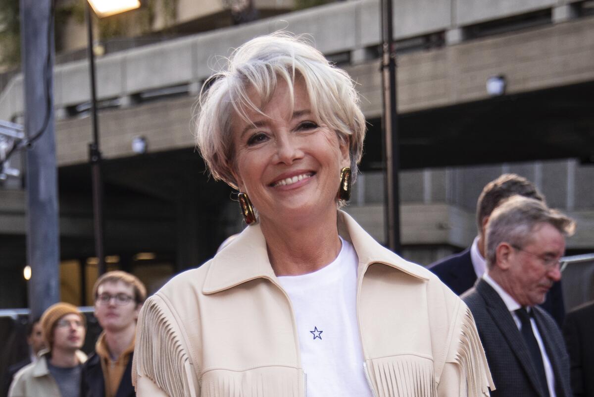 A smiling middle-aged woman with short hair arrives at a premiere