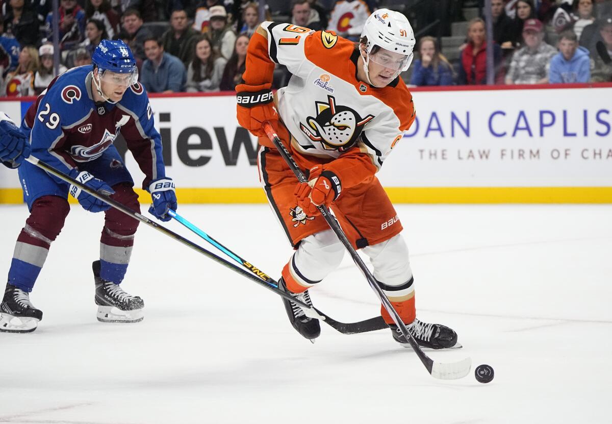 Ducks center Leo Carlsson controls the puck in front of Colorado center Nathan MacKinnon.