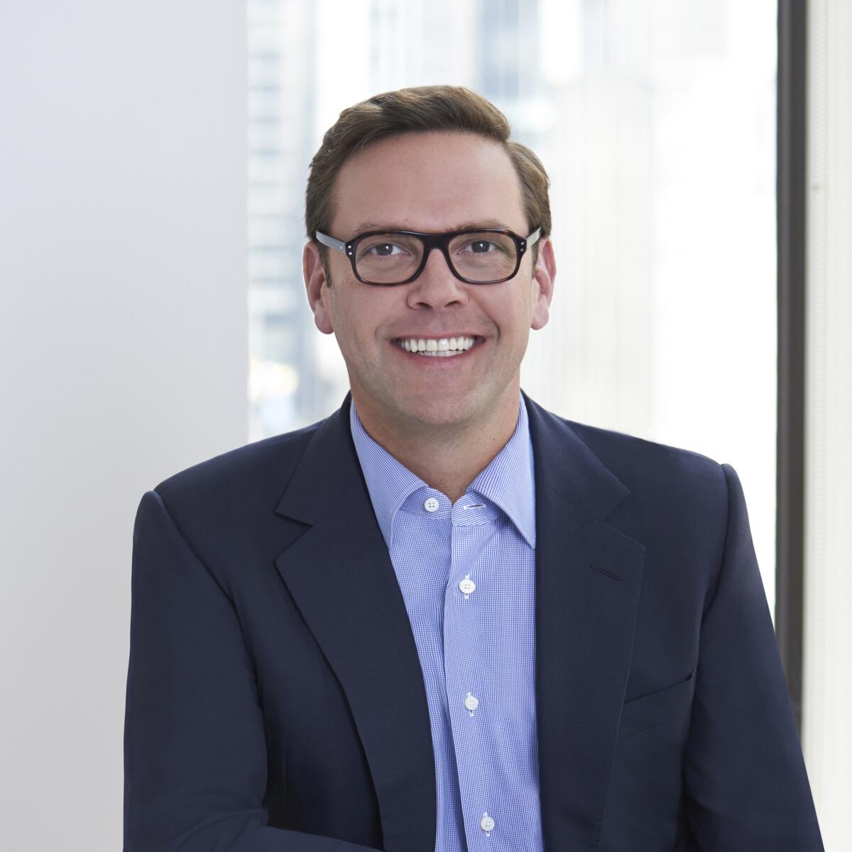 A smiling man wearing a suit and glasses.