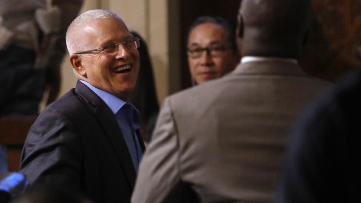 Los Angeles City Councilman Mike Bonin, left, smiles after the Los Angeles City Council unanimously approved an ordinance regulating Airbnb and other home-sharing platforms.