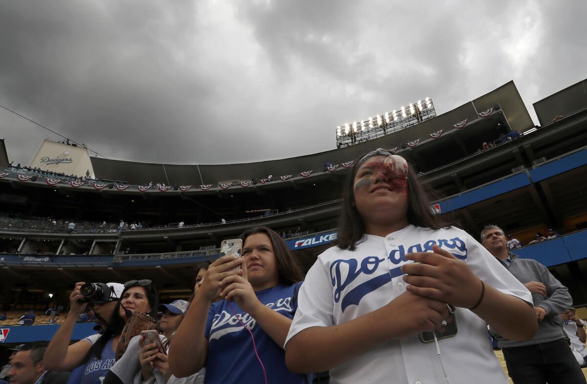 Dodger fans dressed for Halloween watch batting practice under cloudy skies before Game 6.