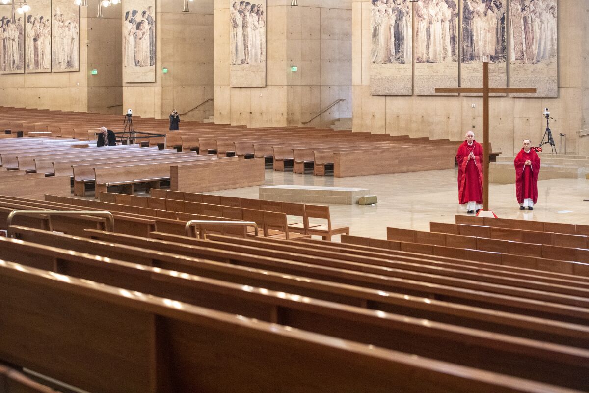 Two clergy members in red robes in an otherwise empty cathedral