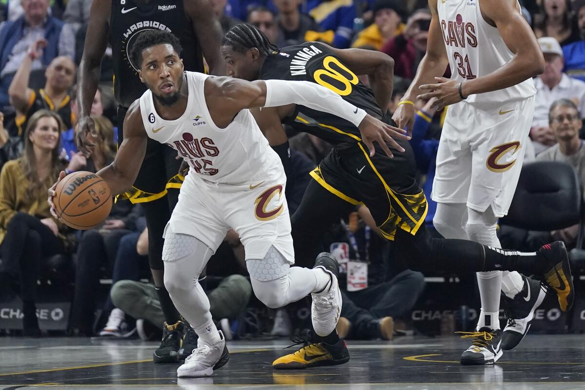 Cleveland Cavaliers guard Donovan Mitchell, left, brings the ball up the court in front of Golden State Warriors forward Jonathan Kuminga (00) during the first half of an NBA basketball game in San Francisco, Friday, Nov. 11, 2022. (AP Photo/Jeff Chiu)