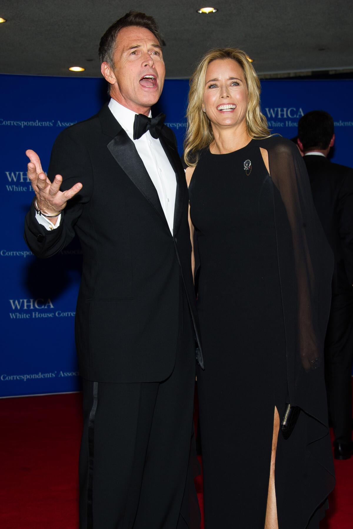 Tim Daly in a tuxedo posing with his mouth open and his right hand to his side. He stands next to Téa Leoni in a black gown.