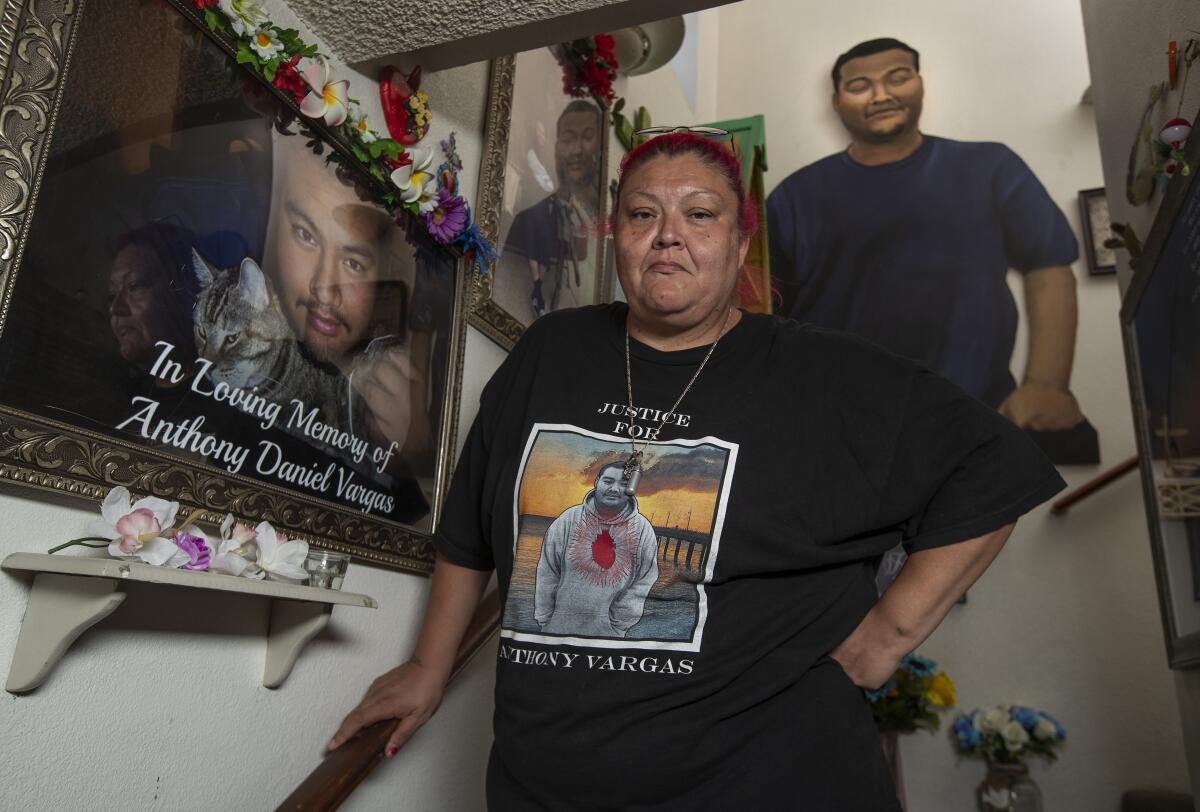 Lisa Vargas stands on the stairs in her home, wearing a T-shirt with an image of her son who was killed by sheriff's deputies