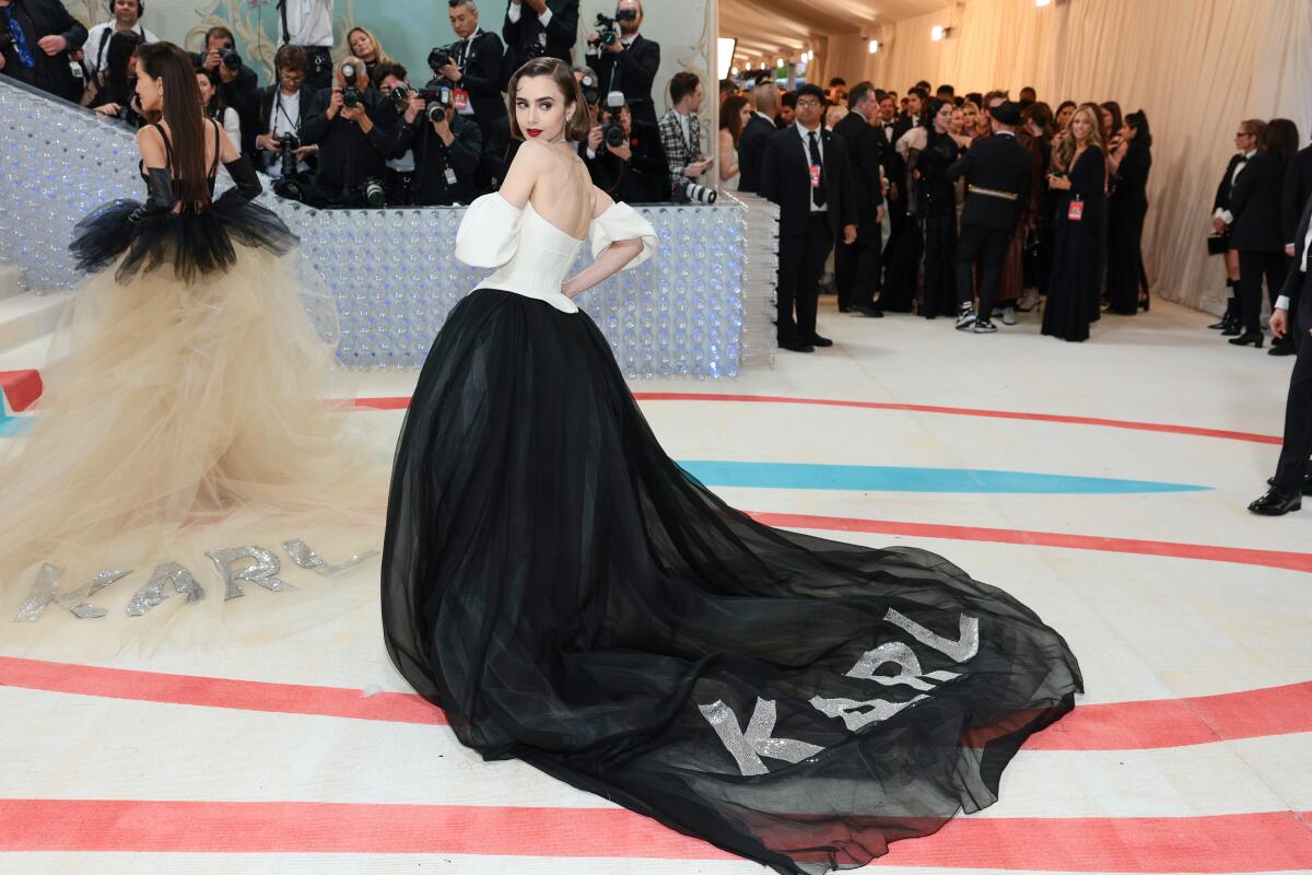 Lily Collins wears a gown with a bedazzled "Karl" adorned to the train of her dress. 