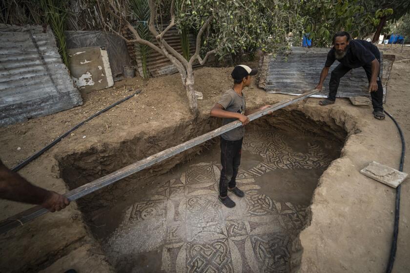 Palestinians clean around a Byzantine-era mosaic floor that was uncovered recently by a farmer in Bureij in central Gaza Strip, Sept. 5, 2022. The man says he stumbled upon it while planting an olive tree last spring and quietly excavated it over several months with his son. Experts say the discovery of the mosaic — which includes 17 well-preserved images of animals and birds — is one of Gaza's greatest archaeological treasures. They say it's drawing attention to the need to protect Gaza's antiquities, which are threatened by a lack of resources and the constant threat of fighting with Israel. (AP Photo/Fatima Shbair)