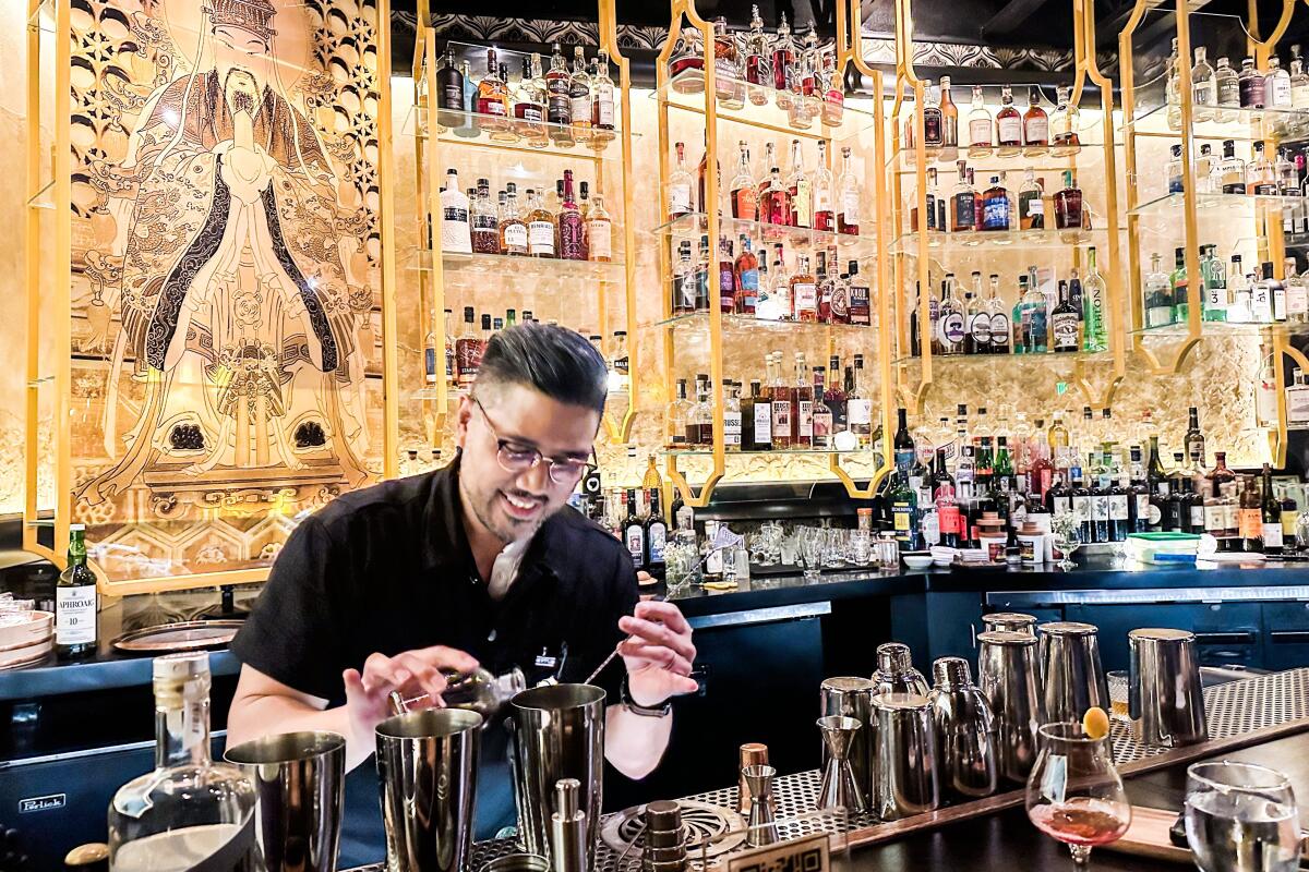 Bartender Brian Prugalidad mixes a cocktail at the bar of Realm of the 52 Remedies.