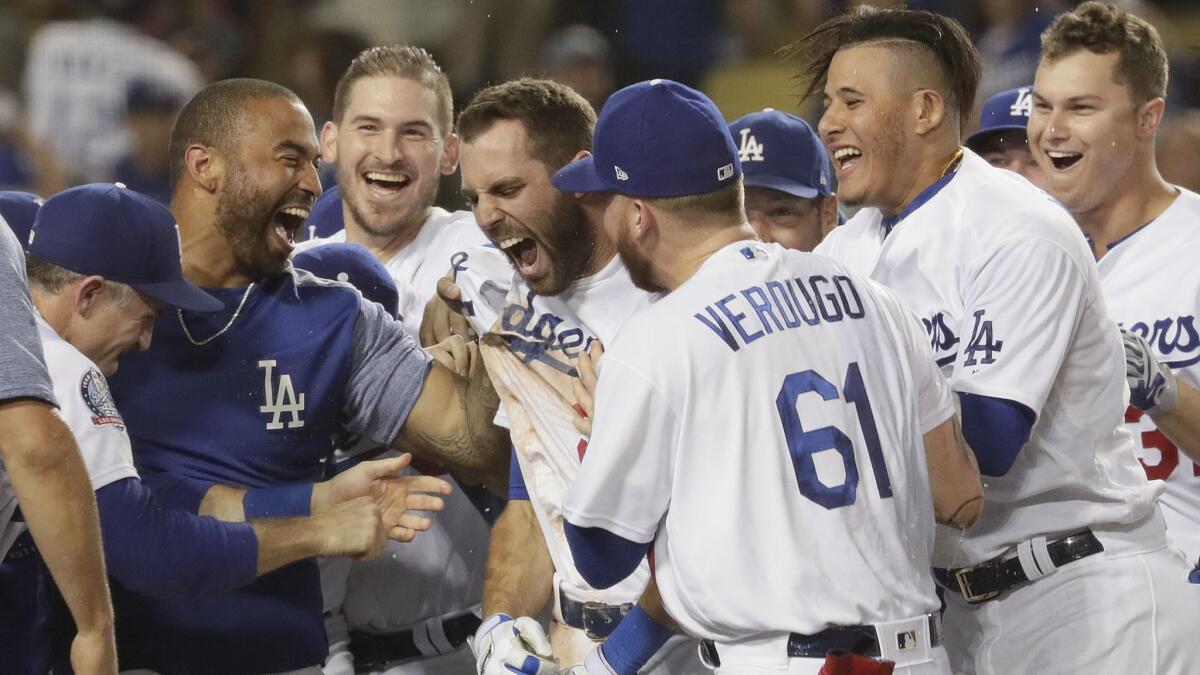 Teammates mob Dodgers second baseman Chris Taylor after he hit a walk-off homer in the 10th inning to beat the Rockies 3-2 at Dodger Stadium on Tuesday.