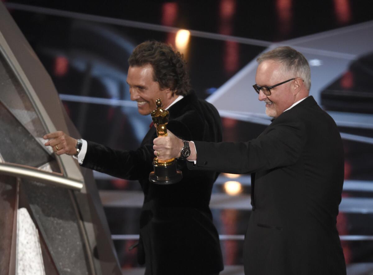 Matthew McConaughey, left, gestures to the audience as Lee Smith holds up his Oscar for film editing on "Dunkirk" at the 90th Academy Awards.
