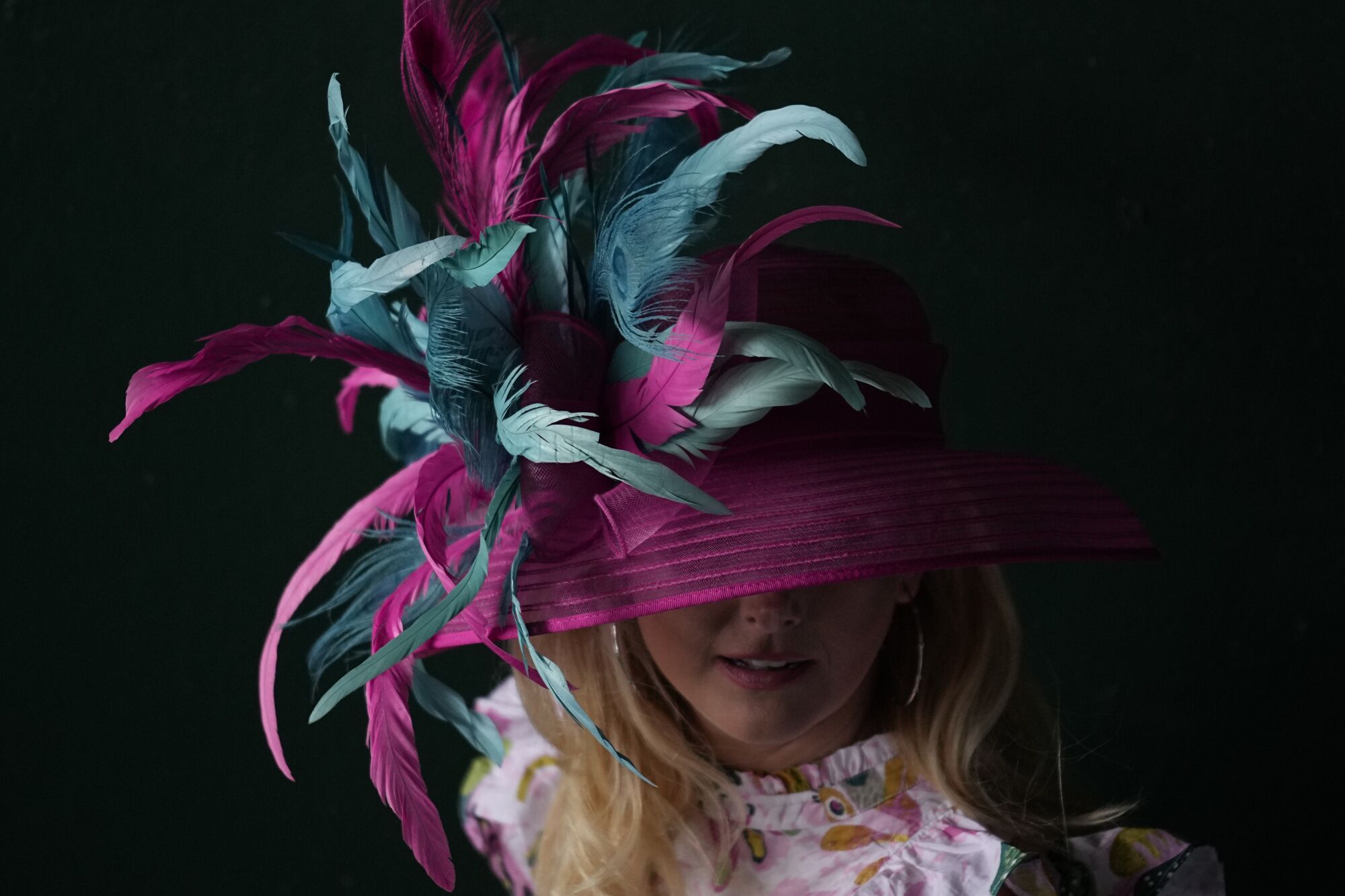 A woman wears a hat featuring a mix of pink and turquoise feathers at the Kentucky Derby on Saturday.
