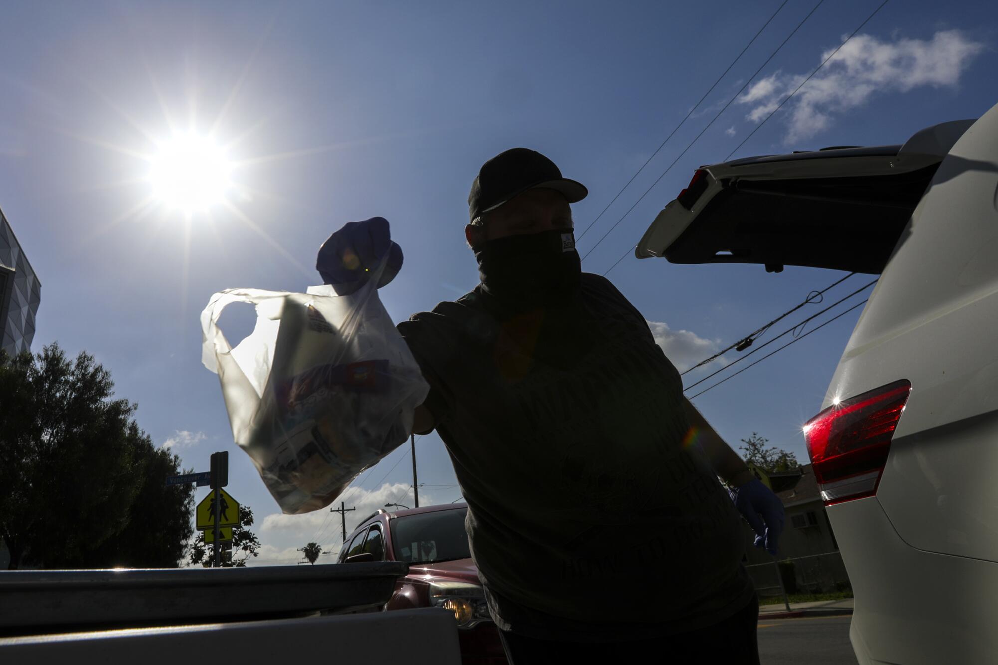 A man grabs meal bags distributed by LAUSD James A. Garfield High School in Los Angeles