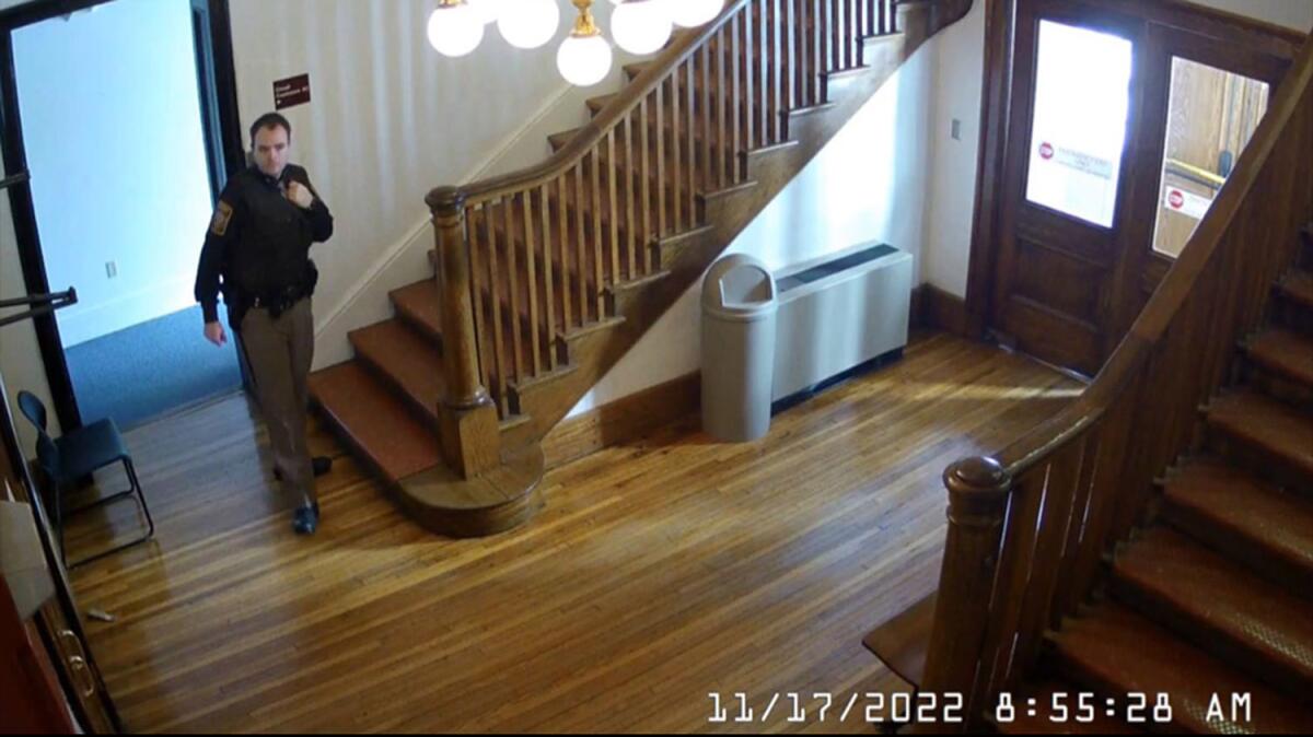 In a still from a surveillance video, a man in a sheriff deputy's uniform walks across a wood floor.