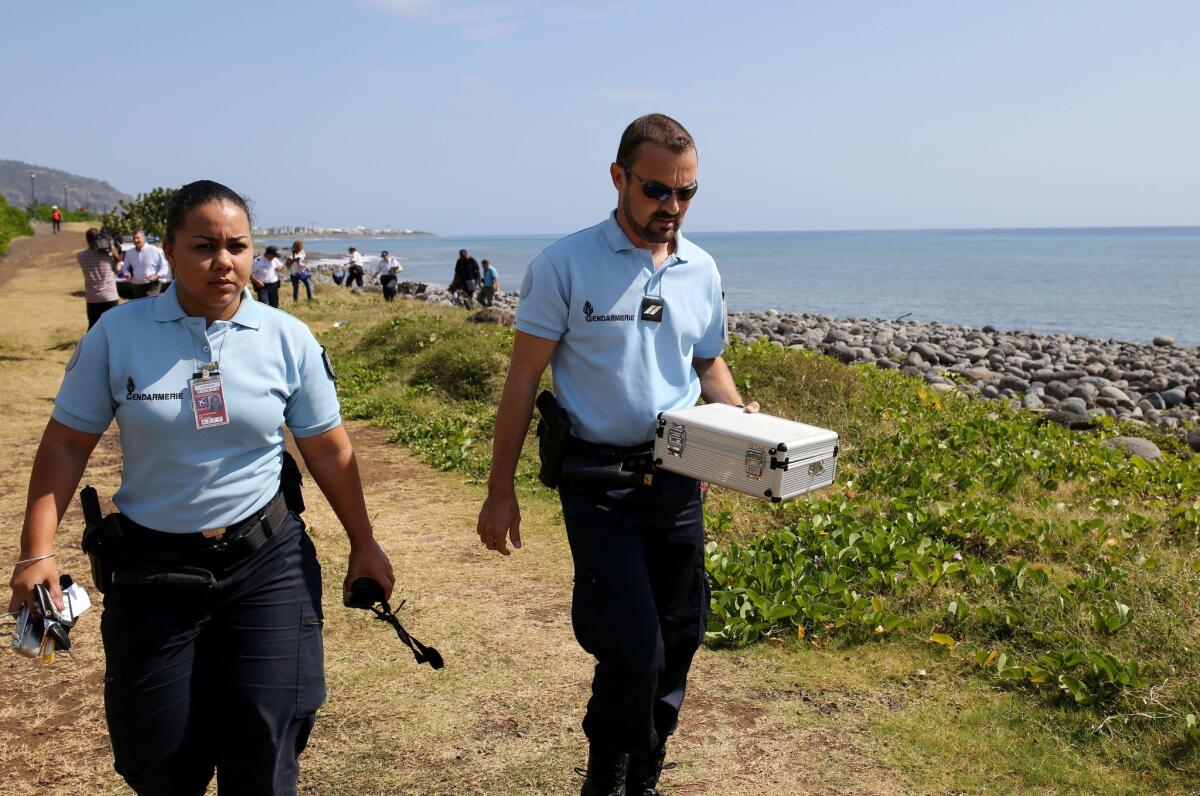 Police officers leave the scene with a container holding metallic debris found on a beach in Saint-Denis on Reunion Island in the Indian Ocean.