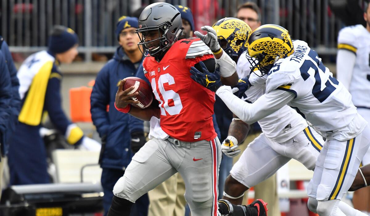 Ohio State's J.T. Barrett carries the ball during the Buckeyes' overtime win against Michigan on Saturday. The Buckeyes kept a firm grip on their No. 2 playoff ranking; the Wolverines fell to No. 5.