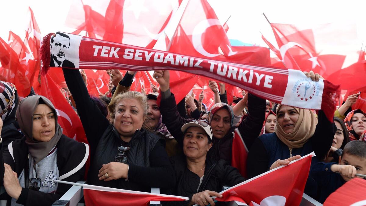 Supporters of Turkish President Tayyip Erdogan wave national flags as they wait for his arrival at the presidential palace in Ankara on Monday.