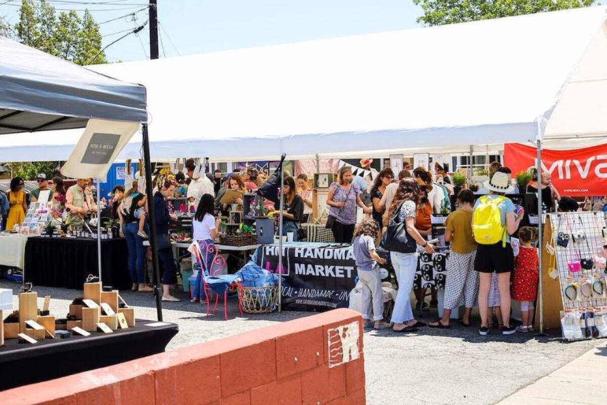 People shop at vendor tables in the parking lot of Hugo's Tacos in Atwater Village.