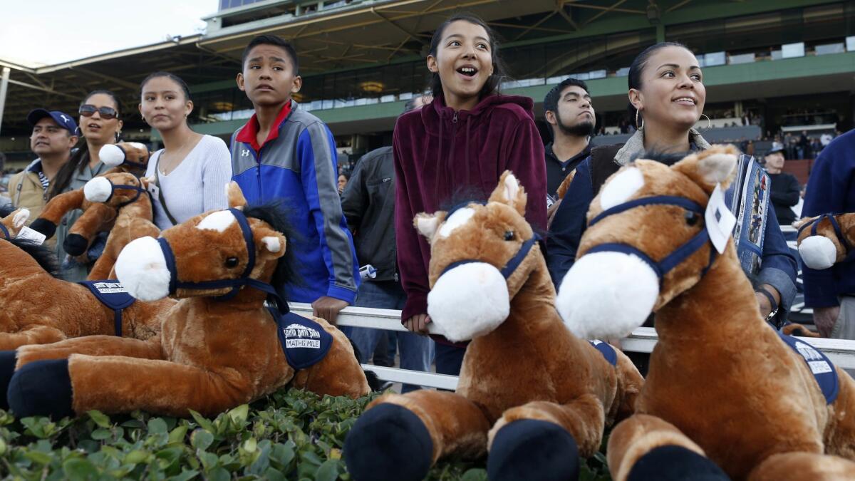 Jessica Orozco, 11, center, and Estela Vigil, right, watch the La Brea Stakes (Grade I), sixth race, on Opening Day at Santa Anita Park.