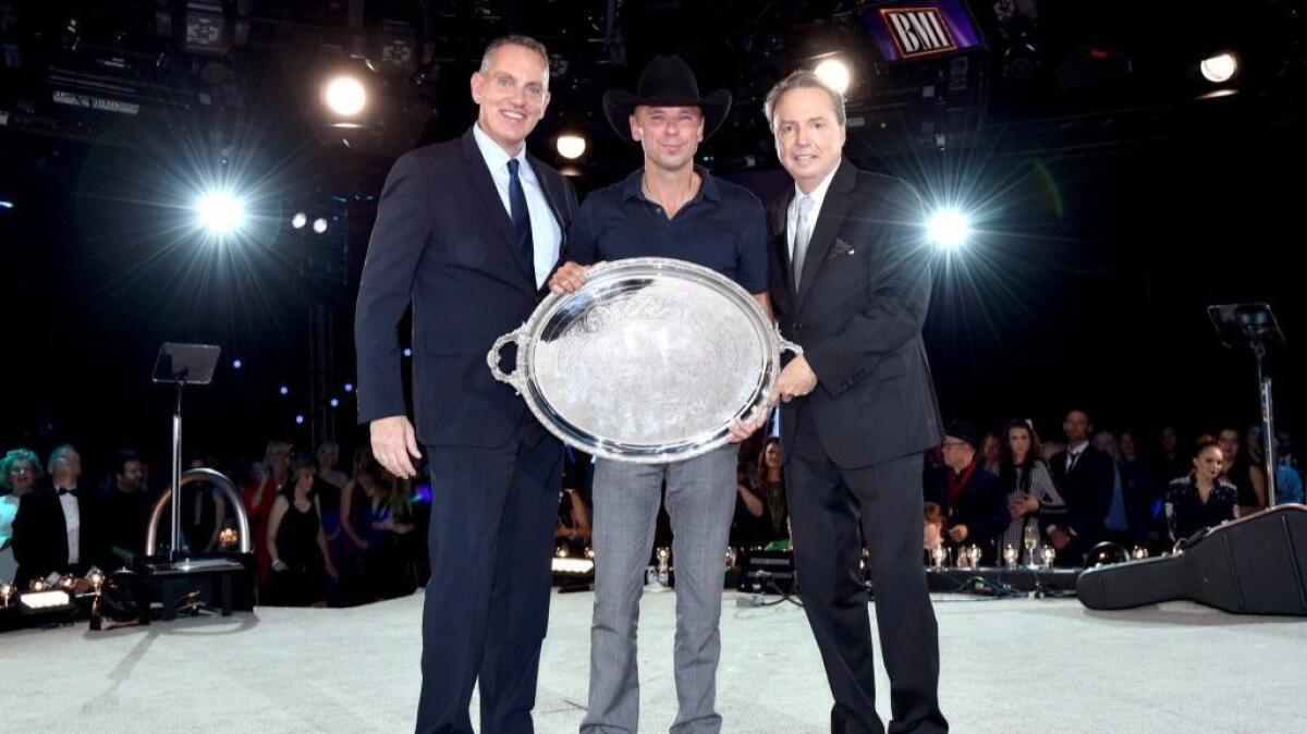 Kenny Chesney, center, is flanked by Michael O’Neill, president and chief executive of BMI, left, and Jody Williams, vice president, writer/publisher relations at BMI, at the 64th BMI Country Awards in Nashville on Tuesday.