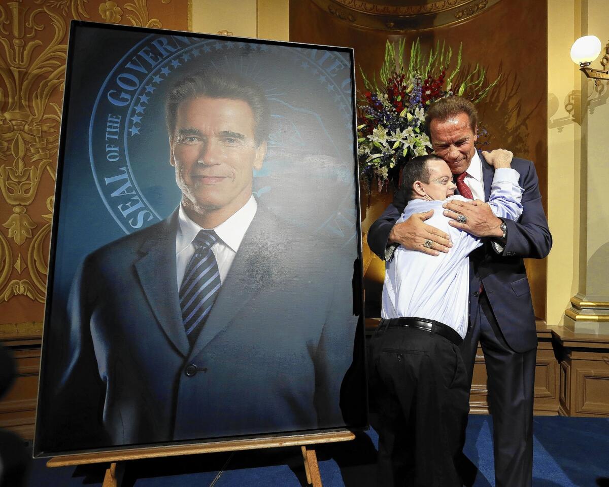Former Gov. Arnold Schwarzenegger gets a hug from John Masterson, 28, who has Down syndrome, after he unveiled his official portrait at the Capitol