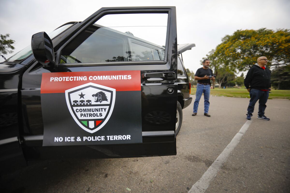 Members of Union del Barrio San Diego stand outside one of the vehicles they used to drive the streets in and around the Shelltown neighborhood on July 4. The volunteer community organization wa looking for activity by Immigration and Customs Enforcement agents, documenting it, when they find it, and informing the community.