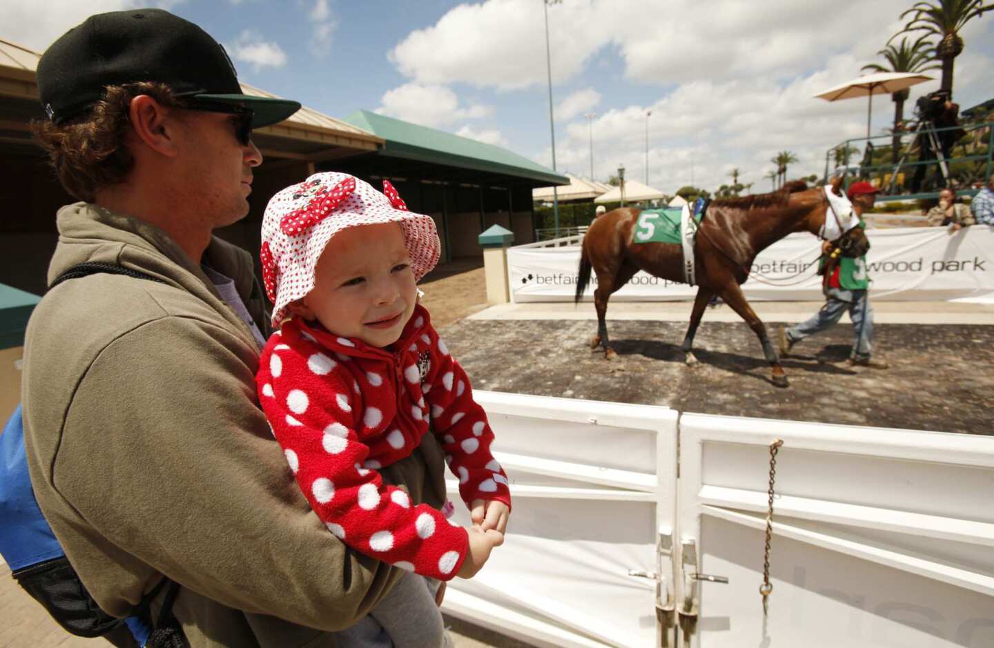 Bobby Summers of El Segundo brings his nearly 2-year-old daughter to watch the horses on opening day at Betfair Hollywood Park on Thursday.