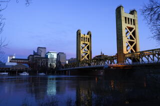 A view of a bridge with tall columns and buildings in the background