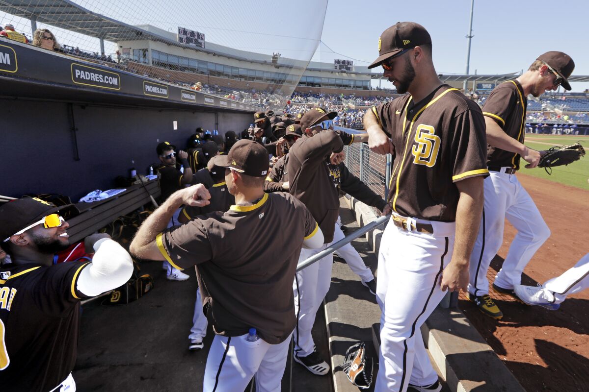Padres players practice good hygiene as they bump elbows rather than slap hands while heading into the dugout between innings of Wednesday's game against the Royals.