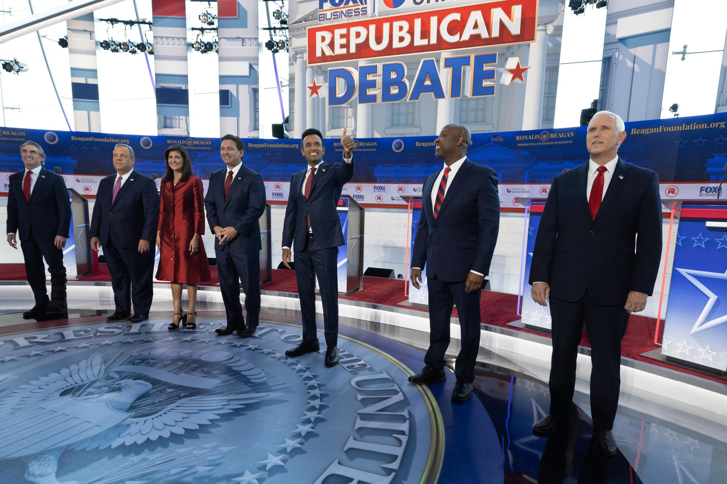 Seven candidates standing in a row onstage below a sign reading "Republican Debate"
