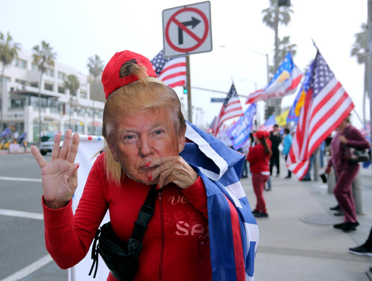 A supporter of President Donald Trump holds a mask of the commander-in-chief.