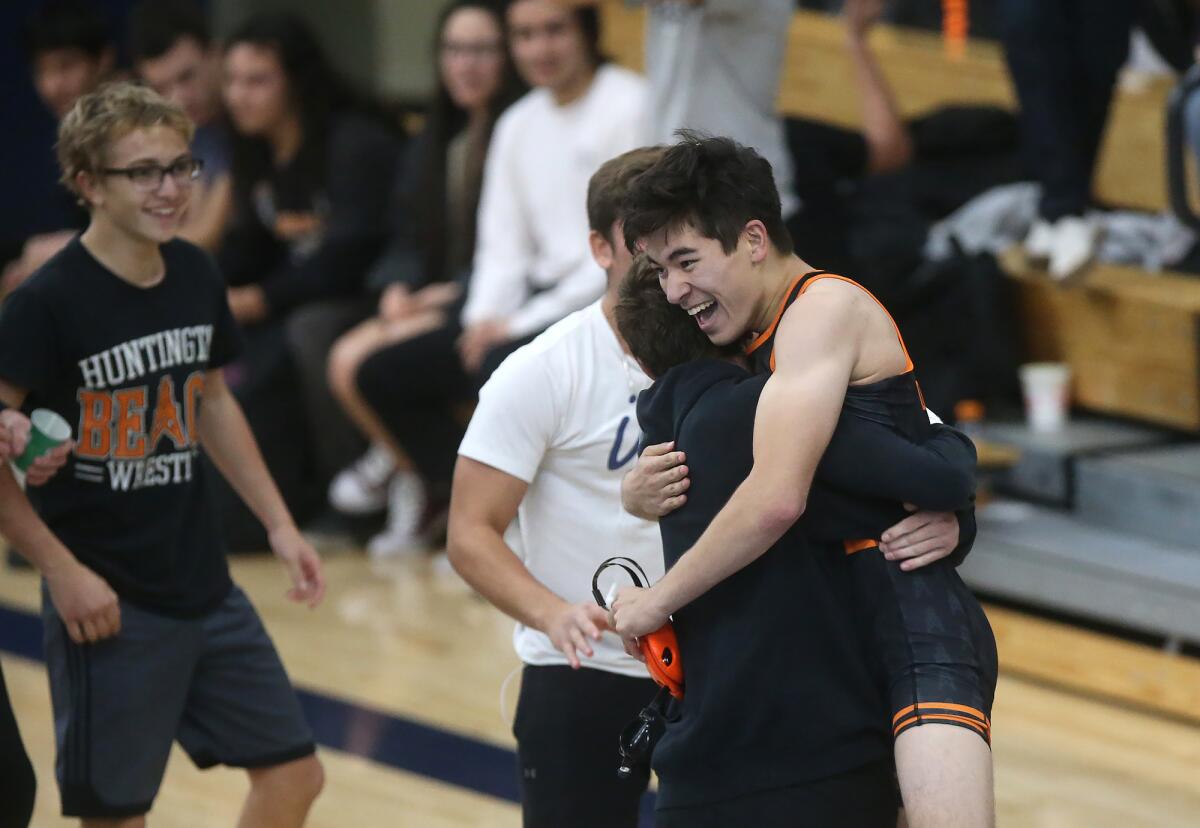Huntington Beach's William Krcelic is lifted by a teammate after he beat Newport Harbor's Luis Nateras in a 138-pound match of the Wave League dual meet in Newport Beach on Wednesday.