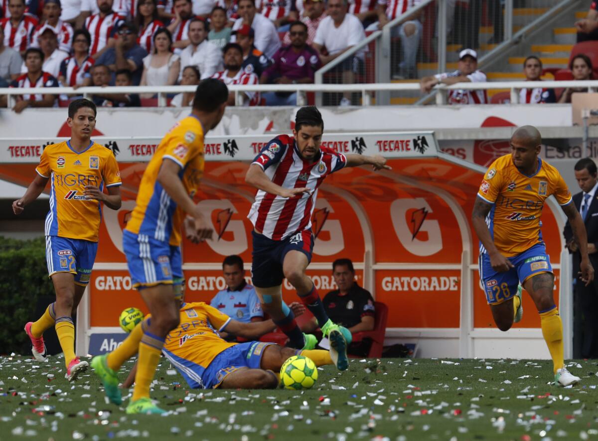 Chivas' Alejandro Zendejas, center fights for the ball with Tigres' Guido Pizzarro, down, during the Mexican soccer league final match in Guadalajara, Mexico, Sunday, May 28, 2017. (AP Photo/Eduardo Verdugo)