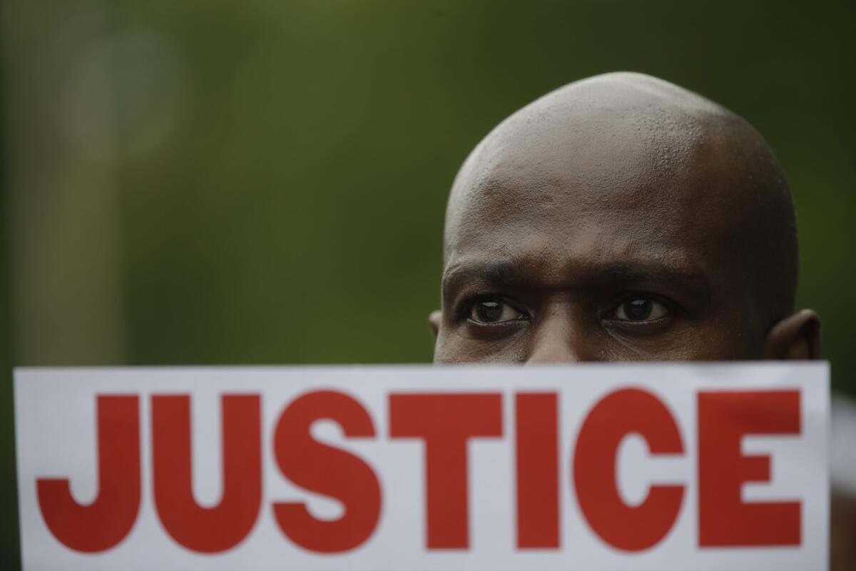 A demonstrator holds a sign calling for justice at a rally in New York on Saturday marking the one-year anniversary of the death of Eric Garner.