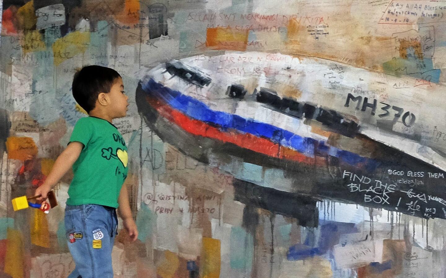 A boy looks at a painting of the missing Flight MH370 aircraft at the viewing gallery of the Kuala Lumpur International Airport in Sepang, outside Kuala Lumpur, on May 23, 2014