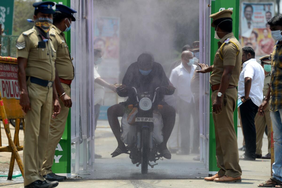 A motorist rides through a spray of disinfectant to protect against the coronavirus in Chennai, India, on Sunday.